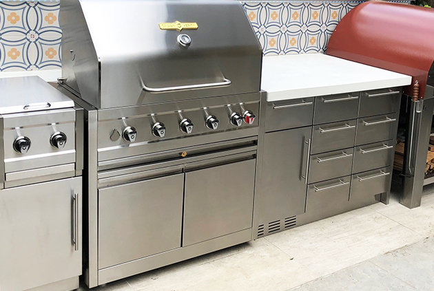 Stainless steel pull out drawers for outdoor kitchen with bbq and backsplash.